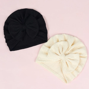 Detail of baby turban hats with large bows in black and cream waffle knit fabric