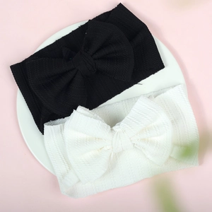 Detailed close-up of black and white baby bow headbands on a white ceramic plate