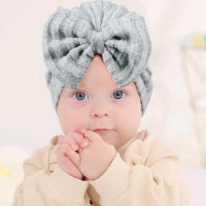 Détail d'un turban gris côtelé pour nouveau-né avec texture douce et grand nœud décoratif