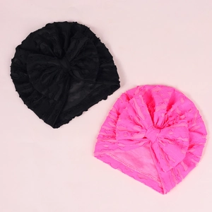 Close-up of black and pink baby turbans featuring soft textured fabric and big bows