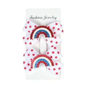 Detail of red star printed bow hair clips with rainbow accents on jewelry card