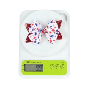 Detail showing weight of the bow hair clip with red blue stars and sequins at 9.9g