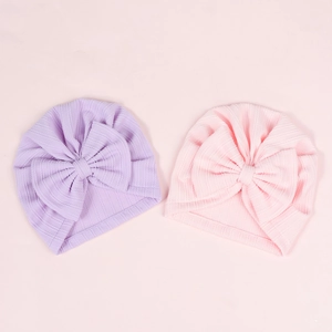 Close-up of soft ribbed baby turban hats with large bows in light purple and pink