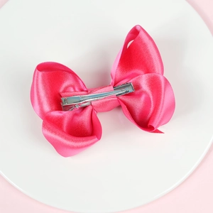 Detail der fuchsienroten Satin-Haarspange mit Doppelschleife und silberner Entenschnabelklemme