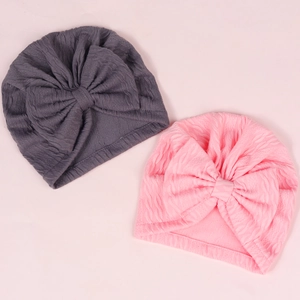 Close-up of baby turban hats with large bows in pink and grey ribbed knit fabric