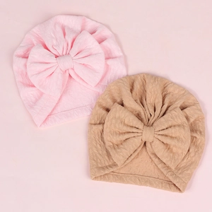 Close-up of pink and tan infant hats featuring soft waffle knit texture and big bows