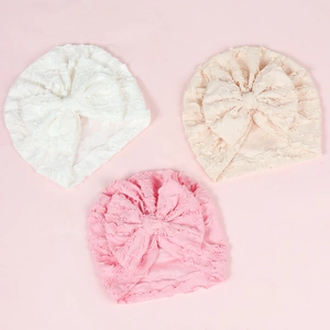 Detailed texture of baby turban hats with large bows in white beige and pink colors