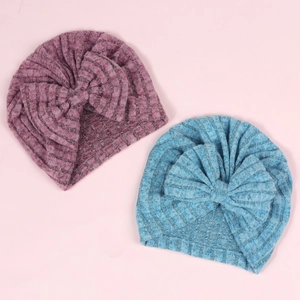 Détail de deux bonnets turban côtelés pour bébé avec grands nœuds en mauve et bleu ciel