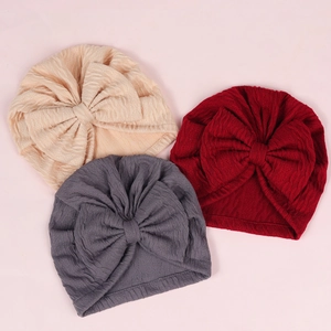 Detailed view of baby turban hats with large bows in beige, burgundy, and dark grey colors