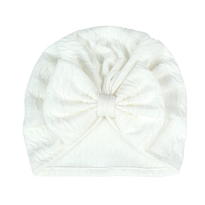 Close-up of white baby turban hat featuring ripple texture and a large bow detail