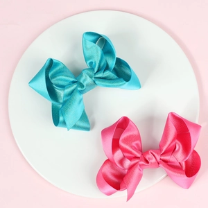 Details von 10cm Glitzer-Haarschleifen in Blau und Rosa auf einer weißen Schale