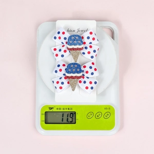 Detail view of 4th of July bow hair clips with ice cream accents on a digital scale