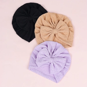Three-pack of baby turban hats with large bows and textured knit fabric in neutral colors