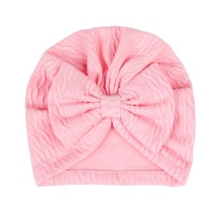 Close-up of pink waffle knit baby turban hat featuring a large soft decorative bow