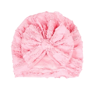 Pink newborn turban hat with ruffled layers and a large decorative bow for baby girls