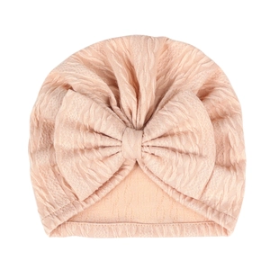 Detail showing peach pink baby turban hat with textured knit and large bow detail