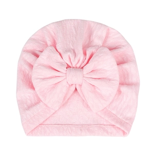 Detail of baby turban hat featuring pink textured knit fabric and large decorative bow