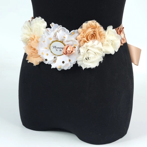 Dettaglio della cintura floreale Mommy To Be con fiori di raso champagne per baby shower