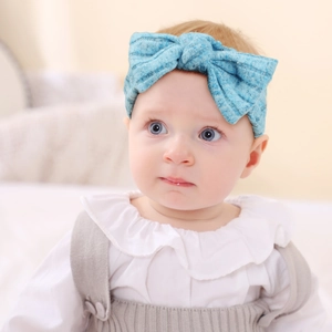 Detail of sky blue ribbed knit baby headband with a large decorative bow design