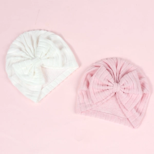 Vue détaillée de la texture en maille côtelée des bonnets turbans roses et blancs pour bébé