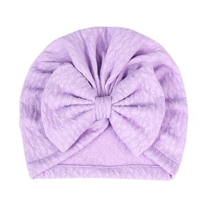 Macro detail of lavender baby hat showing fine knitted texture and large decorative bow