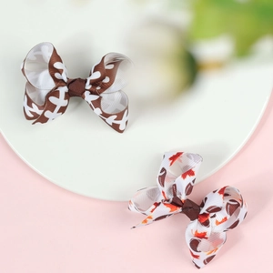 Close-up of 3-inch hair bows with football and autumn maple leaf print patterns