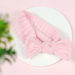 Detail of pink ribbed fabric baby headband featuring a large soft bow on a display tray