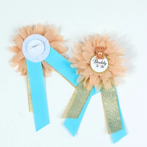 Detail of Daddy To Be floral corsage badge with pink petals and blue ribbons for baby shower