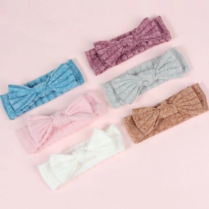 Detail view of six colorful ribbed knit baby bow headbands in soft elastic fabric