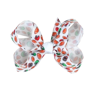Detail of 3-inch white grosgrain ribbon hair bow with colorful football and helmet print