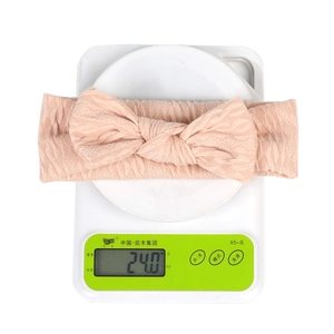 Détail montrant le bandeau bébé à nœud pesant 24 grammes sur une balance de précision