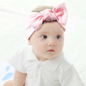 Detail of pink baby headband with large textured bow knot on elastic waffle fabric