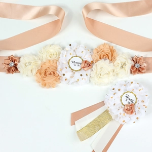 Dettaglio della fascia premaman floreale e badge Mommy To Be per baby shower in champagne