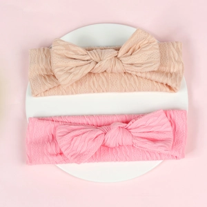 Détail de bandeaux pour bébé rose et beige montrant la texture douce de la maille torsadée