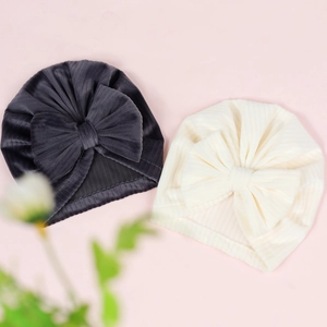 Detailed view of grey and cream ribbed velvet baby hats with large decorative bows