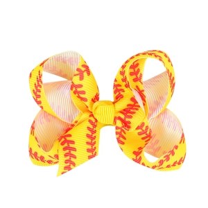 Detailed close-up of yellow ribbon hair bow with baseball stitching print and metal clip
