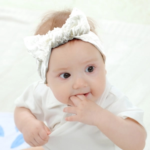 Close-up of white waffle texture baby headband with a large bow on a newborn infant