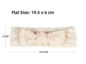 Flat lay detail of a soft pink baby headband with large bow, size 19.5cm by 6cm