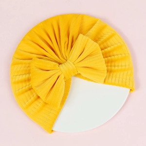 Detailed close-up of ginger yellow corduroy baby turban hat with oversized bow decoration