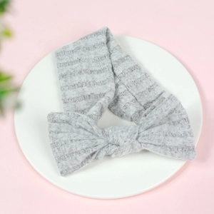 Soft newborn grey rabbit ear headband on a white tray with fresh pink background
