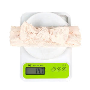 Close-up of pink baby bow headband showing weight of 14.7g on white digital scale