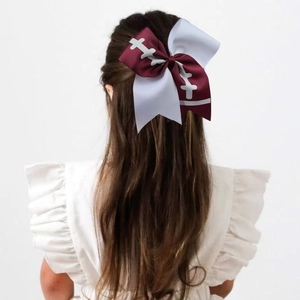 Macro detail of toddler wearing a large rugby-themed bow made of burgundy ribbed ribbon