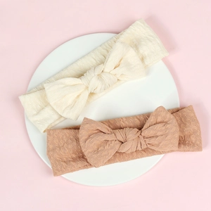 Detail of baby headbands with textured knit fabric and large bows in cream and tan colors