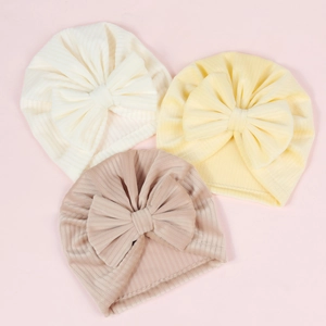 Detailed knit texture of baby turban hats with large bows in beige and soft pink colors