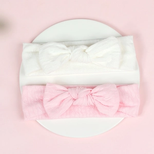 Detail of white and pink infant headbands showing soft honeycomb knit texture and bow knot