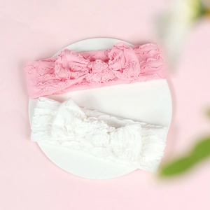 Detail of pink and white baby headbands with large bows on high-elastic ruched fabric