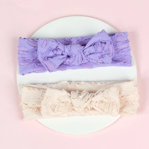 Close-up detail of two elastic baby headbands with textured lace fabric and big bows