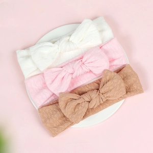 Close-up of baby waffle knit headbands with oversized bows in white, pink and brown