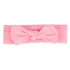 Détail d'un bandeau rose en maille torsadée pour bébé avec un nœud doux élastique