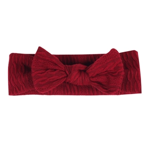 Détail d'un bandeau pour bébé rouge foncé avec un grand nœud sur fond blanc